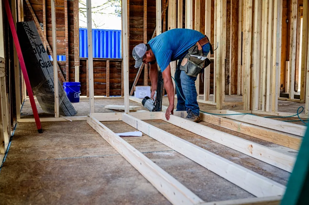 Builder measuring a floor frame inside a home under construction