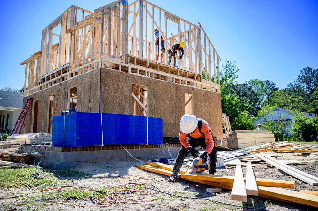 Crew framing a two story home on a ground level slab at a building site