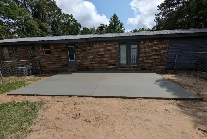 New concrete slab behind a brick ranch house