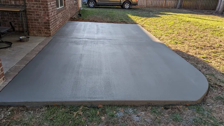 Curved concrete patio at a brick house