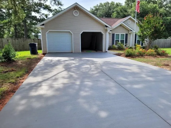 Wide concrete driveway leading to a beige garage