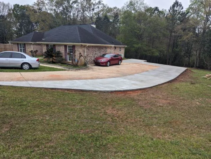 Long curved concrete driveway running to a brick home