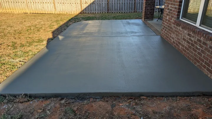 Concrete patio slab along the wall of a brick house