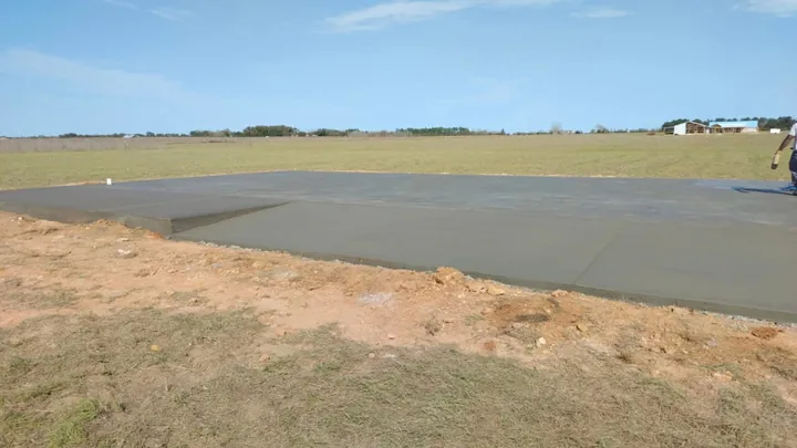 Large finished concrete slab in a field with graded dirt beside it
